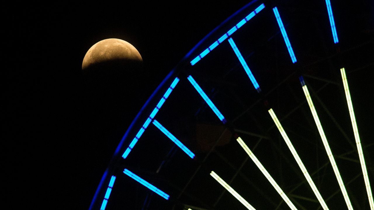  दो साल से अधिक समय में पहला पूर्ण चंद्रग्रहण एक कॉस्मिक शो के लिए सुपरमून के साथ हुआ और यहां इसे अमेरिका के कैलिफोर्निया में फेरिस व्हील के पीछे देखा जा सकता है।  (एपी फोटो/रिंगो एचडब्ल्यू चिउ)