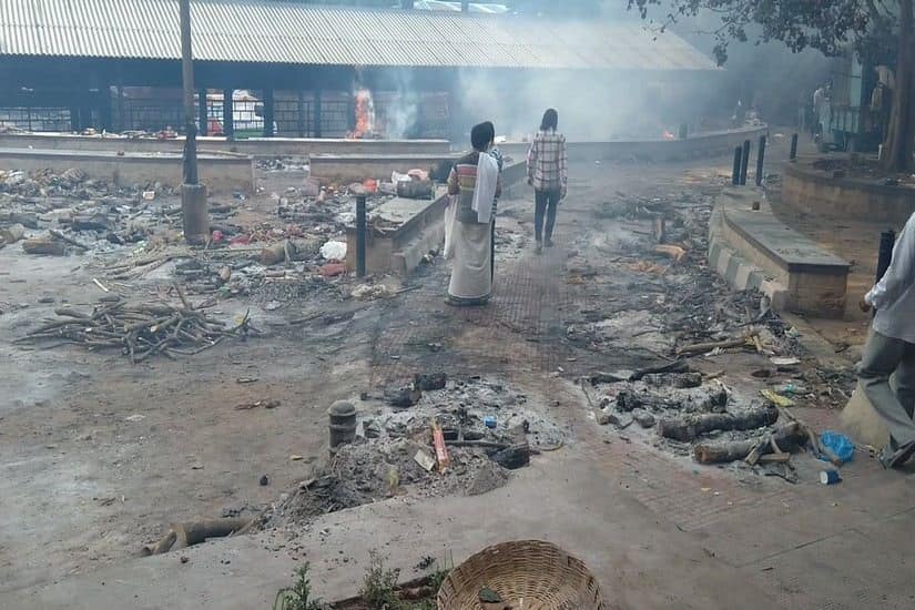  People walk past pyres that were burnt on the footpaths of Chamrajpet crematorium in Bengaluru. Image courtesy: Alithea Mounika 