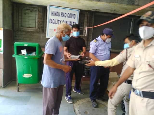 Civil Defence volunteers (in uniform) distributing food at the Hindu Rao Covid ward. Firstpost