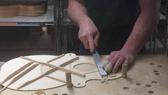 At the C.F Martin & Co. factory in Nazareth, Pennsylvania, internal braces are shaved underneath the soundboard. Such braces provide the instrument with structural reinforcement, but also influence tone. Photo courtesy: Authors via The Conversation 