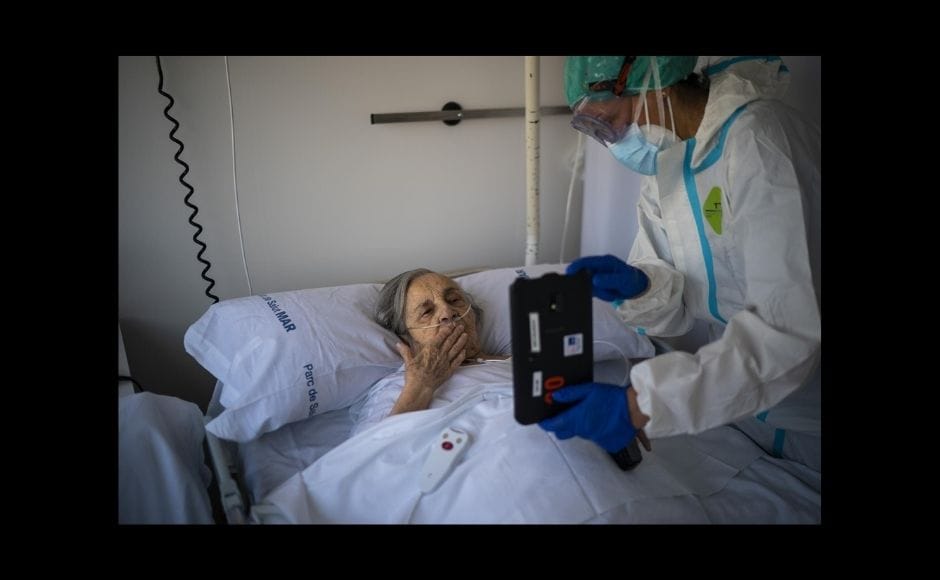 Traveling by scooter around Barcelona, Morenatti captured images of an older couple hugging and kissing through a plastic sheet, mortuary workers in hazmat gear removing bodies and of people enduring the crisis in isolation. | In the picture: Nurse Marta Fernandez holds up a tablet computer over the chest of 94-year-old Maria Teresa Argullos Bove so that she can speak to her sister, children and grandchildren from her hospital bed at the COVID-19 ward at the hospital del Mar in Barcelona, Spain, on 18 November, 2020. The image was part of a series by Associated Press photographer Emilio Morenatti that won the 2021 Pulitzer Prize for feature photography. Photo via The Associated Press/Emilio Morenatti Traveling by scooter around Barcelona, Morenatti captured images of an older couple hugging and kissing through a plastic sheet, mortuary workers in hazmat gear removing bodies and of people enduring the crisis in isolation. | In the picture: Nurse Marta Fernandez holds up a tablet computer over the chest of 94-year-old Maria Teresa Argullos Bove so that she can speak to her sister, children and grandchildren from her hospital bed at the COVID-19 ward at the hospital del Mar in Barcelona, Spain, on 18 November, 2020. The image was part of a series by Associated Press photographer Emilio Morenatti that won the 2021 Pulitzer Prize for feature photography. Photo via The Associated Press/Emilio Morenatti