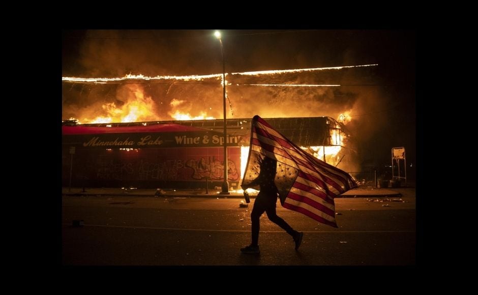 The AP photographers who won in the breaking news category captured the drama and raw emotion of protests that roiled U.S. cities after the May 2020 death of George Floyd, a Black man murdered by a Minneapolis police officer. | In the picture: A protester carries a US flag upside down, a sign of distress, next to a burning building, 28 May, 2020, in Minneapolis. Protests over the death of George Floyd, a black man who died in police custody, broke out in Minneapolis for a third straight night. The image was part of a series of photographs by The Associated Press that won the 2021 Pulitzer Prize for breaking news photography. Photo via The Associated Press/Julio Cortez The AP photographers who won in the breaking news category captured the drama and raw emotion of protests that roiled U.S. cities after the May 2020 death of George Floyd, a Black man murdered by a Minneapolis police officer. | In the picture: A protester carries a US flag upside down, a sign of distress, next to a burning building, 28 May, 2020, in Minneapolis. Protests over the death of George Floyd, a black man who died in police custody, broke out in Minneapolis for a third straight night. The image was part of a series of photographs by The Associated Press that won the 2021 Pulitzer Prize for breaking news photography. Photo via The Associated Press/Julio Cortez