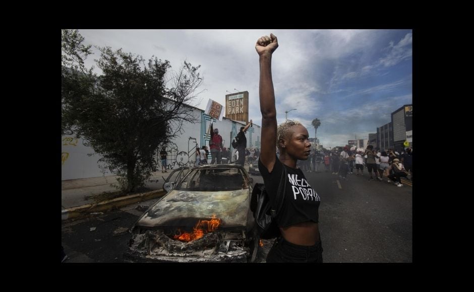 AP photographers captured close-up images of demonstrators with fists in the air and sometimes violent conflicts with police. One widely published photograph by Julio Cortez on the night of 28 May in riot-torn Minneapolis shows a lone, silhouetted protester running with an upside-down American flag past a burning liquor store. | In the picture: A protester raises her fist in the air next to a burning police vehicle in Los Angeles, 30 May, 2020, during a demonstration over the death of George Floyd. The image was part of a series of photographs by The Associated Press that won the 2021 Pulitzer Prize for breaking news photography. Photo via The Associated Press/Ringo H.W. Chiu AP photographers captured close-up images of demonstrators with fists in the air and sometimes violent conflicts with police. One widely published photograph by Julio Cortez on the night of 28 May in riot-torn Minneapolis shows a lone, silhouetted protester running with an upside-down American flag past a burning liquor store. | In the picture: A protester raises her fist in the air next to a burning police vehicle in Los Angeles, 30 May, 2020, during a demonstration over the death of George Floyd. The image was part of a series of photographs by The Associated Press that won the 2021 Pulitzer Prize for breaking news photography. Photo via The Associated Press/Ringo H.W. Chiu