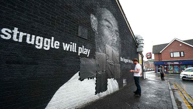 Ed Wellard, from Withington, tapes bin liners across offensive wording on the mural of Manchester United striker and England player Marcus Rashford on the wall of the Coffee House Cafe on Copson Street. AP