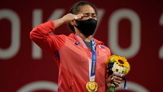 Hidilyn Diaz of Philippines gestures on the podium as she listen to the national anthem after winning the gold medal in the women’s 55kg weightlifting event. AP