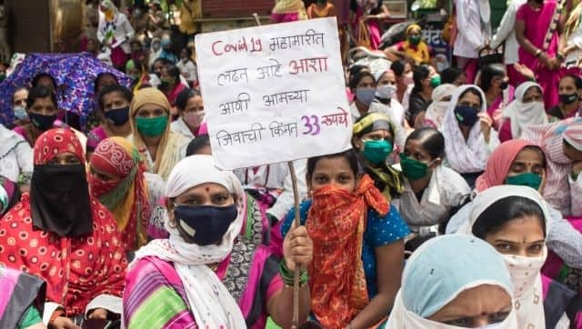 A protesting ASHA worker with a placard that reads, “ASHA workers are fighting COVID, and their life’s value is only Rs 33.”