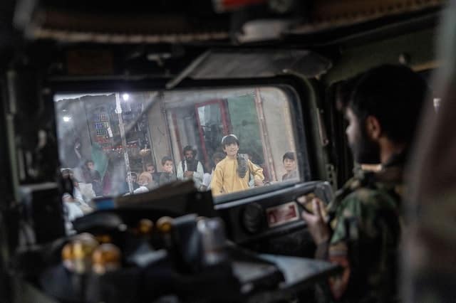 People watch as the convoy of Afghan Special Forces passes through a market during a combat mission against Taliban, in Kandahar province. Image courtesy: Danish Siddiqui/Reuters