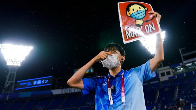 A worker holds a “mask on” sign during the medal ceremony for baseball at the at the 2020 Tokyo Olympics. AP