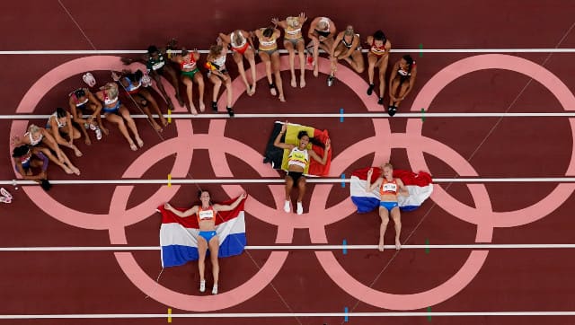 Athletes participating in women's heptathlon pose around the Olympic rings at the end of the event. AP