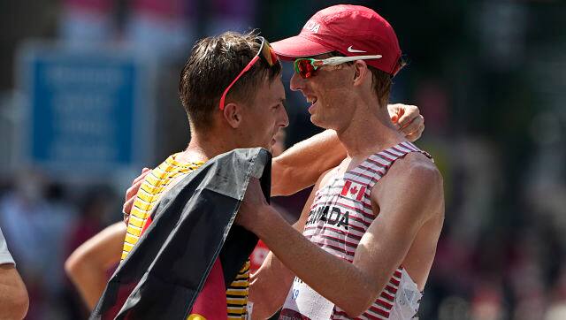 Jonathan Hilbert of Germany, left, and Evan Dunfee of Canada, celebrate after crossing the finish line second and third respectively in the men’s 50km race walk. AP