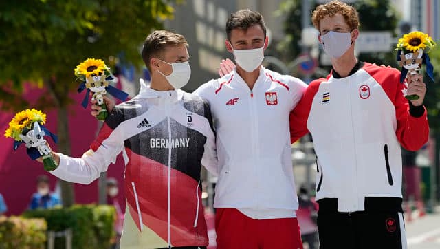Gold medallist Dawid Tomala of Poland, center, silver medalist Jonathan Hilbert of Germany, left, and bronze medalist Evan Dunfee of Canada, pose with flowers during the flower ceremony for the men’s 50km race walk. AP