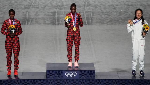Gold medallist Jepchirchir of Kenya, middle, silver medalist Brigid Kosgei, left, of Kenya and bronze medalist Molly Seidel of USA, pose for a photo during the closing ceremony in the Olympic Stadium. AP/Charlie Riedel
