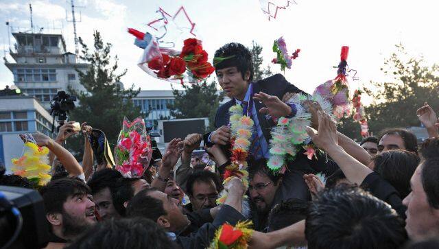 Afghanistan Olympic taekwondo bronze medallist Rohullah Nikpai (C) waves as he returns home at Kabul’s airport on August 14, 2012 following the completion of the 2012 London Olympic Games. Nikpai won the country’s only medal as part of the six-strong Afghanistan Olympic team.    AFP PHOTO / Massoud HOSSAINI (Photo by MASSOUD HOSSAINI / AFP)