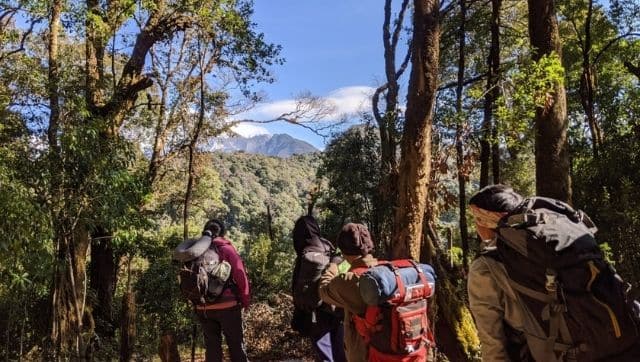 The team from Thanamir village hike through the community forest to set up camera traps that monitor wildlife. Image credit: Ramya Nair.