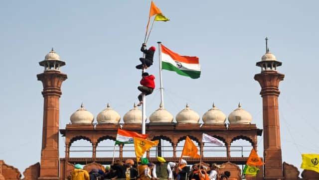 Protesters climb a flagpole at the ramparts of the Red Fort on Republic Day. AFP