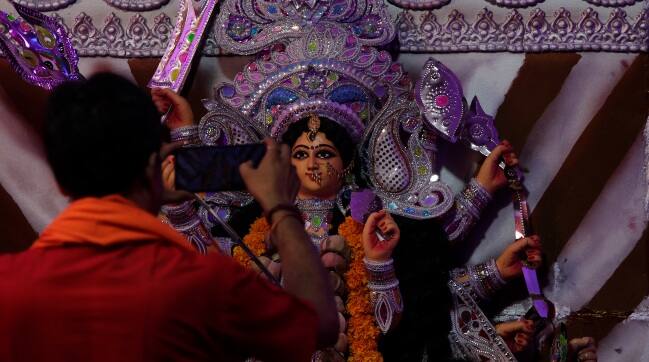A Hindu priest takes photograph of an idol of goddess Durga during Durga Puja festival in Mumbai. AP 
