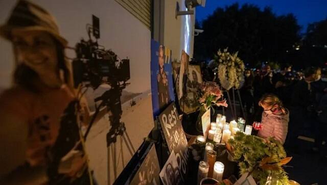 A girl pays respects near a photo of cinematographer Halyna Hutchins, at a memorial table during a candlelight vigil in her memory in Burbank, California on October 24, 2021 (AFP/DAVID MCNEW)