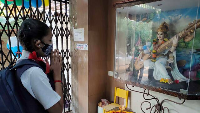 A girl seeks blessings from Goddess Saraswati before the start of classes at the school. The schools in Mumbai were reopened for students from classes eight to 12. Image credit: Sachin Gokhale 