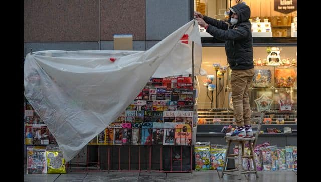 A vendor covers a newsstand with a plastic sheet on a shopping street in Vienna. AP