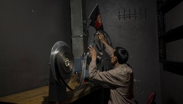 Rahmatullah Ezati plays back a film roll in the projectionist room of the Ariana Cinema in Kabul, Afghanistan on Monday, Nov. 8, 2021. The cinema’s staff still show up at work every day hoping they will eventually get paid, despite the Taliban’s orders to stop operating. (AP Photo/Bram Janssen)