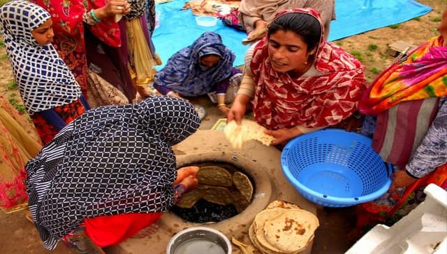 Afghan women baking bread (naan), in a ground tandoor (oven). Every family (if can afford it) have maximum two tandoors in their home. One inside the house in a separate room known as “ woorjai” or a fireplace, and one outside the house as an outdoor kitchen. That is because in summer they bake bread outside the home and inside during winter. Image courtesy: Mudasir Rawloo 