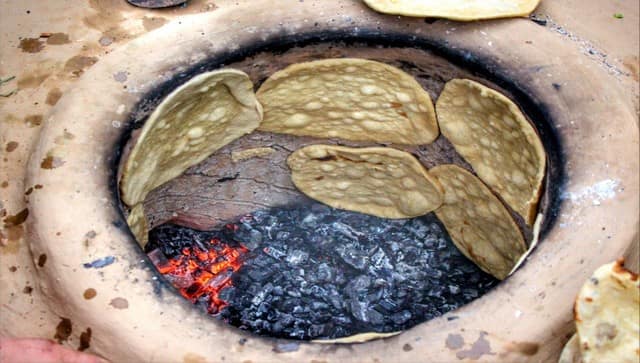 Fresh nan bread sticks to the inside of a hot tandoori oven and slowly cooks on the hot oven wall. Image courtesy: Mudasir Rawloo 
