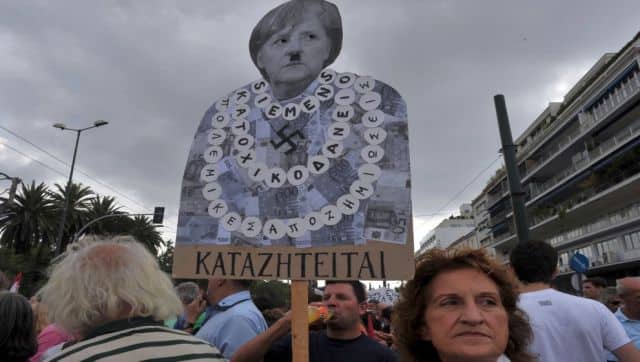 File photo of a protester holding a placard of German Chancellor Angela Merkel featuring a Hitler moustache near the Greek parliament in Athens in 2012. AFP