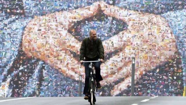 A cyclist rides past a giant billboard featuring German Chancellor Angela Merkel's hands in a trademark pose in Berlin. AFP