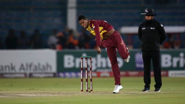 Akeal Hosein, center, bowls while umpire Aleem Dar watches during the first Twenty20 international cricket match between Pakistan and West Indies at the National Stadium, in Karachi, Pakistan, Monday, Dec. 13, 2021. (AP Photo/Fareed Khan)