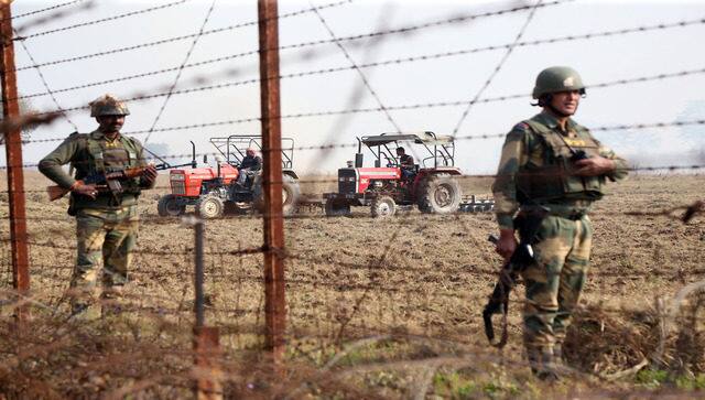 BSF personnel stand guard as farmers work. Image courtesy: Alok Pathania