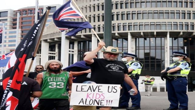 Protesters walk with flags and signs on the grounds around the parliament building (behind) in Wellington against COVID restrictions, inspired by a similar demonstration in Canada. AFP