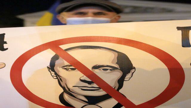 A Ukrainian man holds a poster depicting Russian president Vladimir Putin in Mariupol, Ukraine. AP