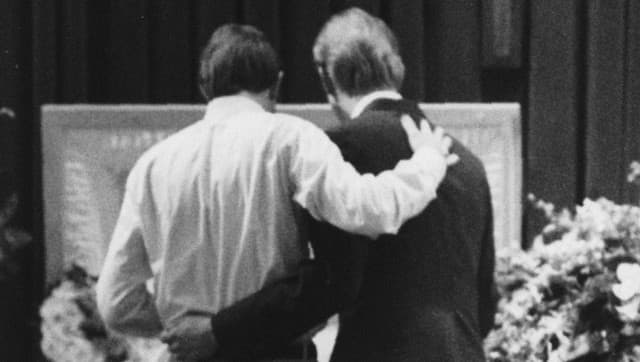 FILE - In this March 11, 1991 file photo, mourners embrace each other next to the casket of AIDS patient David Thurmond during his funeral service in Houston. (AP Photo/Houston Chronicle, John Everett)