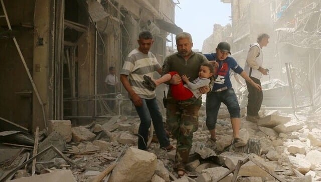 A Syrian man carries a child as they evacuate an area following a reported airstrike on 22 April, 2016 in Syria’s second city Aleppo. AFP