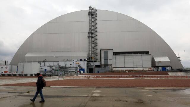 ON HOLD TO GO WITH UKRAINE CHERNOBYL STORY A man walks past a shelter construction covers the exploded reactor at the Chernobyl nuclear plant, in Chernobyl , Ukraine, Thursday, April 15, 2021. April 26 marks the 35th anniversary of the Chernobyl nuclear disaster. A reactor at the Chernobyl nuclear power plant exploded on April 26, 1986, leading to an explosion and the subsequent fire spewed a radioactive plume over much of northern Europe. (AP Photo/Efrem Lukatsky)