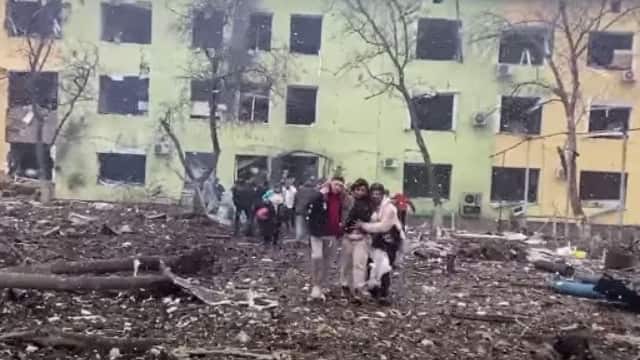 In this video grab from a handout footage taken and released by the the National Police of Ukraine on March 9, 2022, people are helped out of a damaged building of a children's hospital following a Russian air strike in the southeastern city of Mariupol. AFP