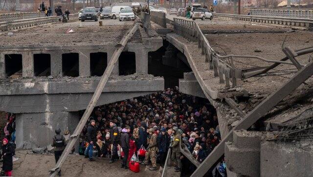 Ukrainians crowd under a destroyed bridge as they try to flee crossing the Irpin river in the outskirts of Kyiv, Ukraine, Saturday, March 5, 2022. (AP Photo/Emilio Morenatti)