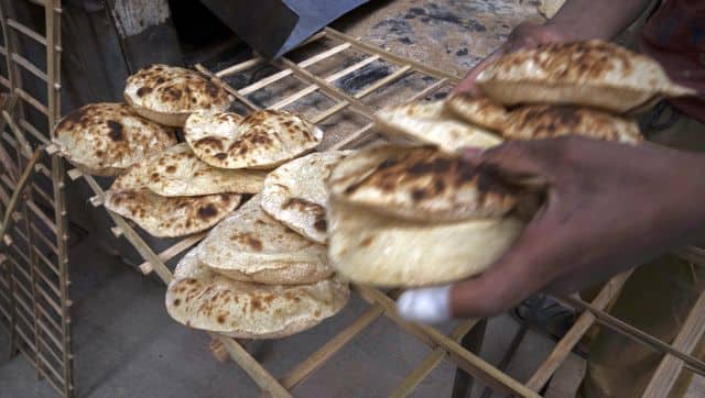 A worker collects Egyptian traditional 'baladi' flatbread, at a bakery, in el-Sharabia, Shubra district, Cairo, Egypt. AP