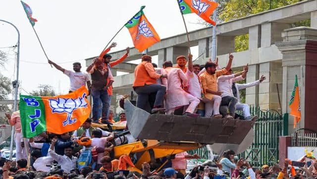 BJP supporters holding party flags ride a bulldozer in celebration, as the party heads to a landslide victory in UP Assembly elections, at the party office, in Lucknow. PTI