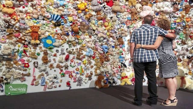 Relatives of those killed when flight MH17 was shot down over Ukraine at the 'hedge of compassion' made of thousands of dolls found along the road and at Schiphol airport. AFP