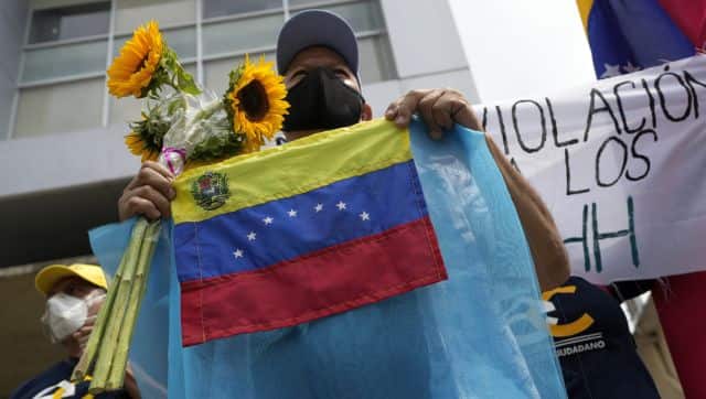 A man holding sunflowers and national flags representing the Ukraine and Venezuela, protest against Russian's invasion of the Ukraine, outside the European Union offices in Caracas, Venezuela. AP