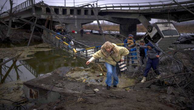 A woman runs as she flees with her family across a destroyed bridge in the outskirts of Kyiv, Ukraine. AP