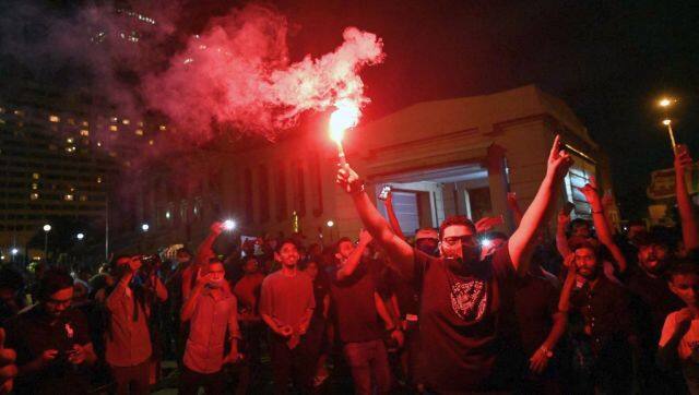Protesters hold flares during a demonstration against the surge in prices and shortage of fuel and other essential commodities at the entrance of the president's office in Colombo. AFP