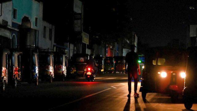 A man walks beside parked auto rickshaws along a road during a power cut in Colombo. AFP