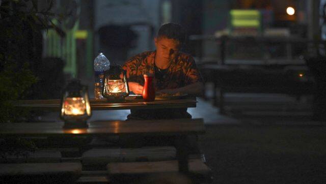 A tourist sits in a restaurant during a power outage in Mirissa, Sri Lanka. AFP