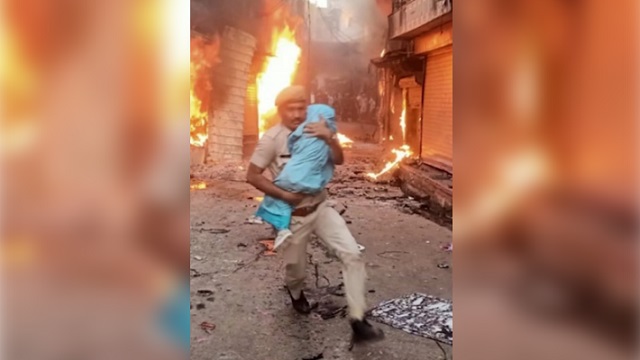 Fearless constable saves baby amid fire and communal clashes in Karauli; netizens salute his spirit Fearless constable saves baby amid fire and communal clashes in Karauli; netizens salute his spirit
