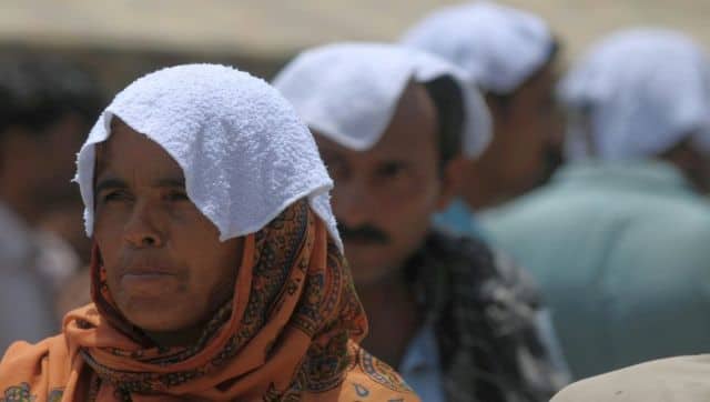 Pakistanis cover their head with wet towels stand outside a hospital during a heatwave in Karachi in 2015. AFP
