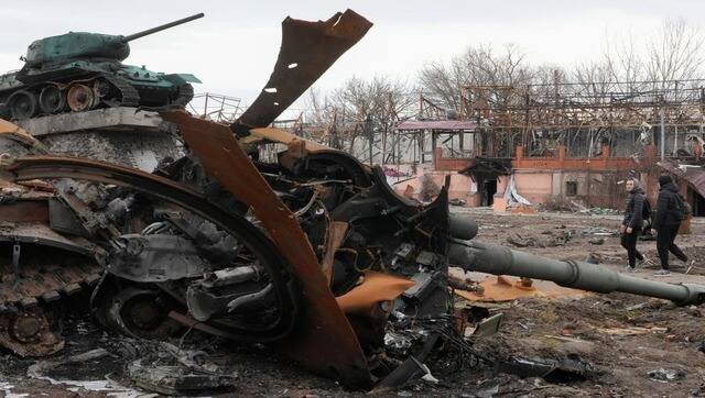 Local residents pass by a damaged Russian tank in a town east of Kyiv. AP