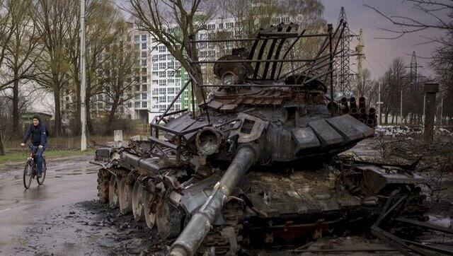 A man rides his bicycle next to a destroyed Russian tank in Chernihiv, Ukraine, on 21 April, 2022. AP