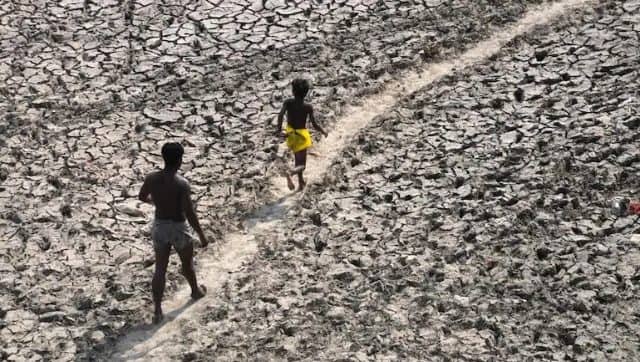 A man and a boy walk across the almost dried up bed of river Yamuna following hot weather in New Delhi, India. AP